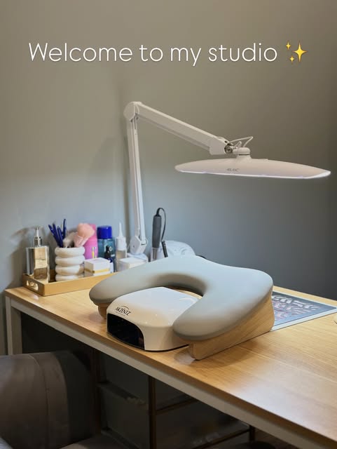 Inside the Lumé studio — a clean, warm-lit workstation with an ergonomic hand rest and E-file setup.